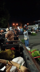 Evening market activity and illuminated statue documented in Mengwi