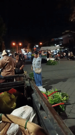 Evening market activity and illuminated statue documented in Mengwi