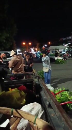 Evening market activity and illuminated statue documented in Mengwi