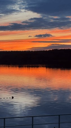 Vivid sunset reflects across calm Klyazma Reservoir