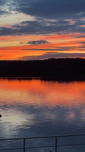 Vivid sunset reflects across calm Klyazma Reservoir