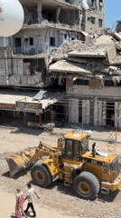 CAT loader and crew work through rubble at Gaza damage site