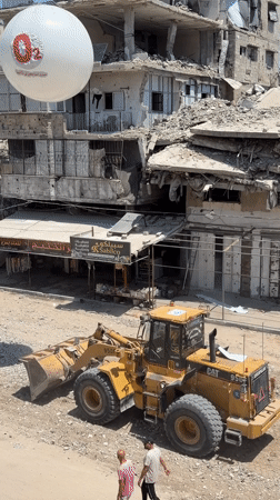 CAT loader and crew work through rubble at Gaza damage site