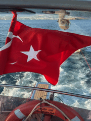 Sailing near Bodrum with a Turkish flag and towed dinghy
