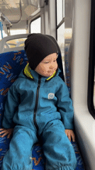 Child in blue snowsuit travels public transport in Rusanovo