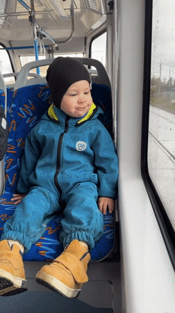 Child in blue snowsuit travels public transport in Rusanovo