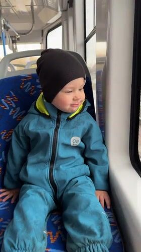Child in blue snowsuit travels public transport in Rusanovo