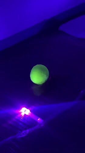 Tennis balls filmed under UV light in Thailand