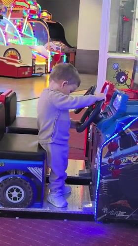 Toddler plays arcade games at entertainment center in Bulgaria