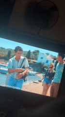 Screen shows coastal village scene with young adults in Kubwa