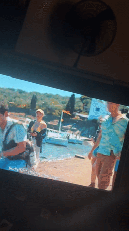 Screen shows coastal village scene with young adults in Kubwa