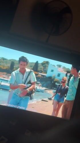 Screen shows coastal village scene with young adults in Kubwa