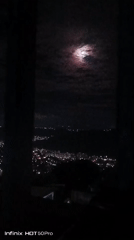 Caracas residents document moonlit cityscape during cloudy night