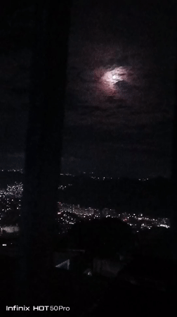 Caracas residents document moonlit cityscape during cloudy night