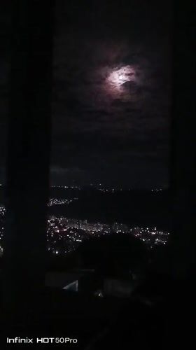 Caracas residents document moonlit cityscape during cloudy night