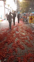 Red petals blanket Barcelona sidewalks near illuminated tower