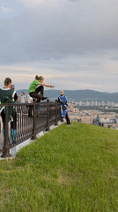 Person checks phone while leaning over railing at Krasnoyarsk overlook