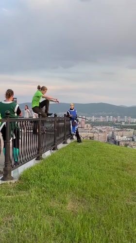 Person checks phone while leaning over railing at Krasnoyarsk overlook