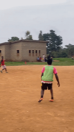 Young men play informal soccer match on dirt field