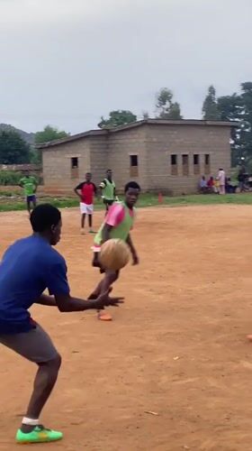 Young men play informal soccer match on dirt field