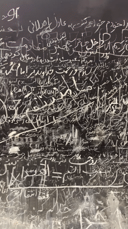 Chalk-written protest slogans cover a dark surface in Tehran