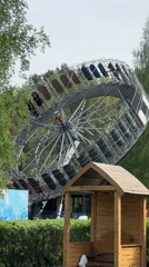 Tilted spinning ride operates with passengers at amusement park