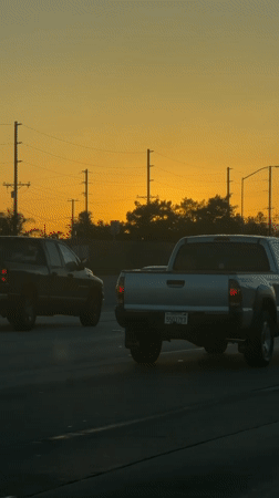 Los Angeles highway traffic flows under colorful sunset sky