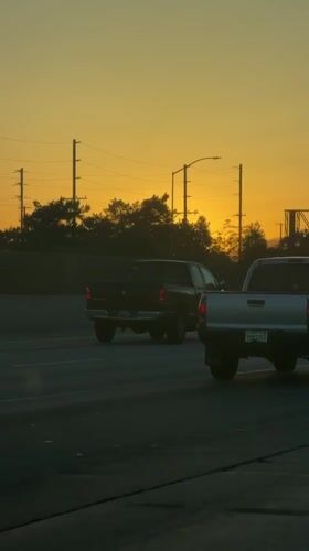 Los Angeles highway traffic flows under colorful sunset sky