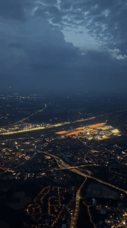 Brussels suburbs glow at night, airport runway visible from above