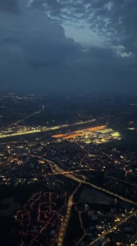 Brussels suburbs glow at night, airport runway visible from above