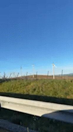 Rural Spanish countryside with wind turbines filmed from moving vehicle