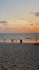 Sunset beach scene with swimmers in Choeng Thale, Thailand