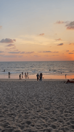 Sunset beach scene with swimmers in Choeng Thale, Thailand