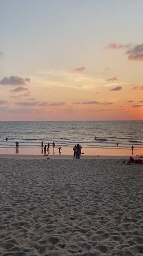 Sunset beach scene with swimmers in Choeng Thale, Thailand