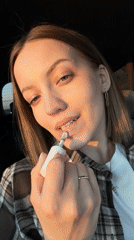 Woman applies lip gloss in car in Rogachovo