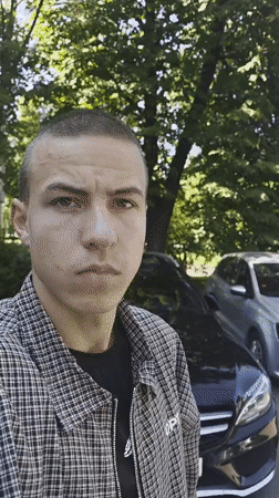 Checkered jacket, serious look, two cars in the background