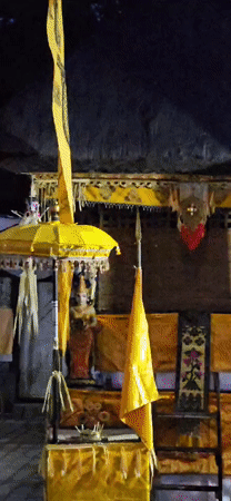 Men prepare traditional decorations at illuminated Balinese temple