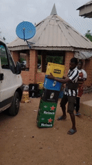 Man carries stacked bottle crates near van in Nigeria