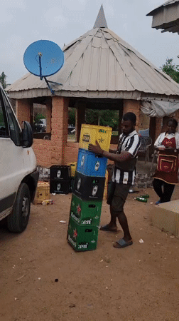 Man carries stacked bottle crates near van in Nigeria