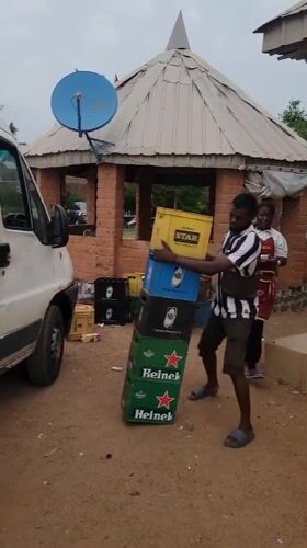 Man carries stacked bottle crates near van in Nigeria