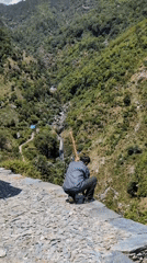 Hiker pauses for mountain valley views near Bhagsu waterfall