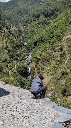 Hiker pauses for mountain valley views near Bhagsu waterfall