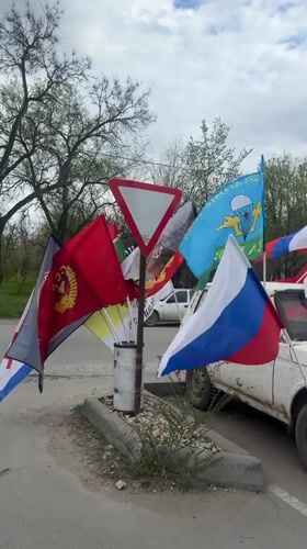 Multiple flags displayed on roadside yield sign in Volgograd