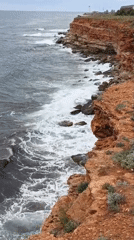 Morning coastal scenes documented along red clay cliffs with lighthouse
