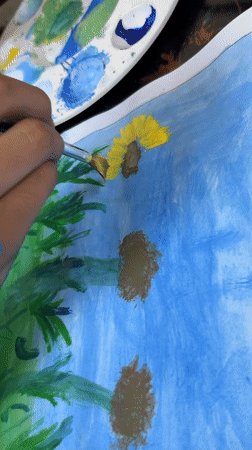 Artist paints sunflowers on blue paper in Guayana City