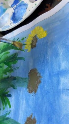 Artist paints sunflowers on blue paper in Guayana City