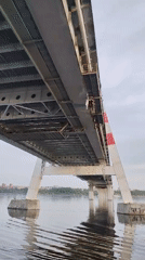 Cable-stayed bridge with red-striped tower documented across water