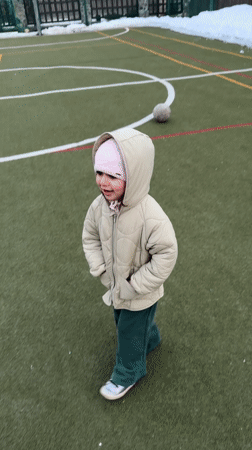 Toddler plays soccer with adults on Russian sports field