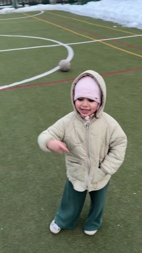 Toddler plays soccer with adults on Russian sports field