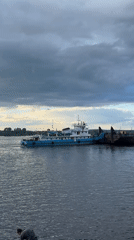 Tugboat pushes barge across Kama River under dramatic skies